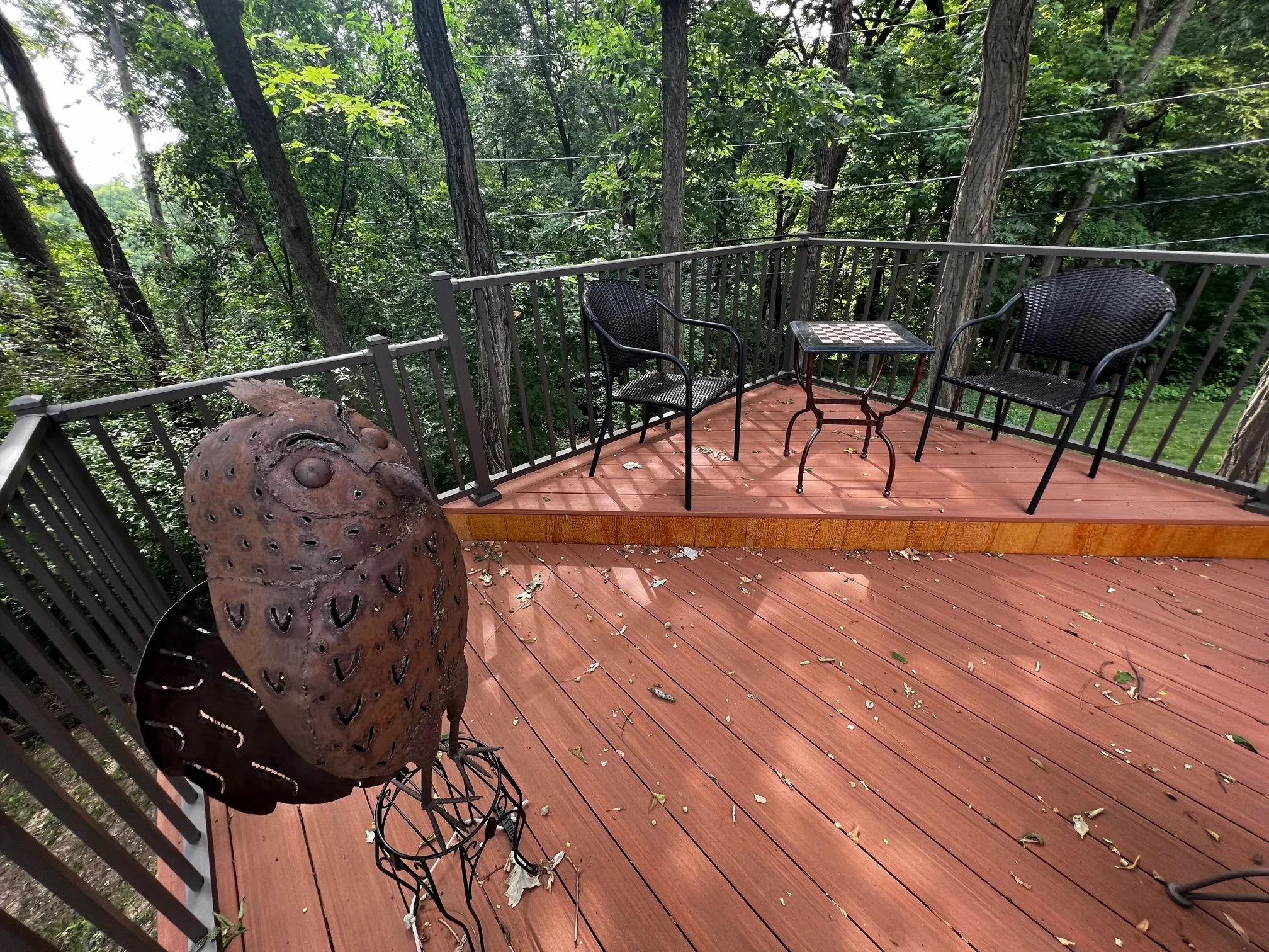 Deck corner with cable railing and seating in the trees