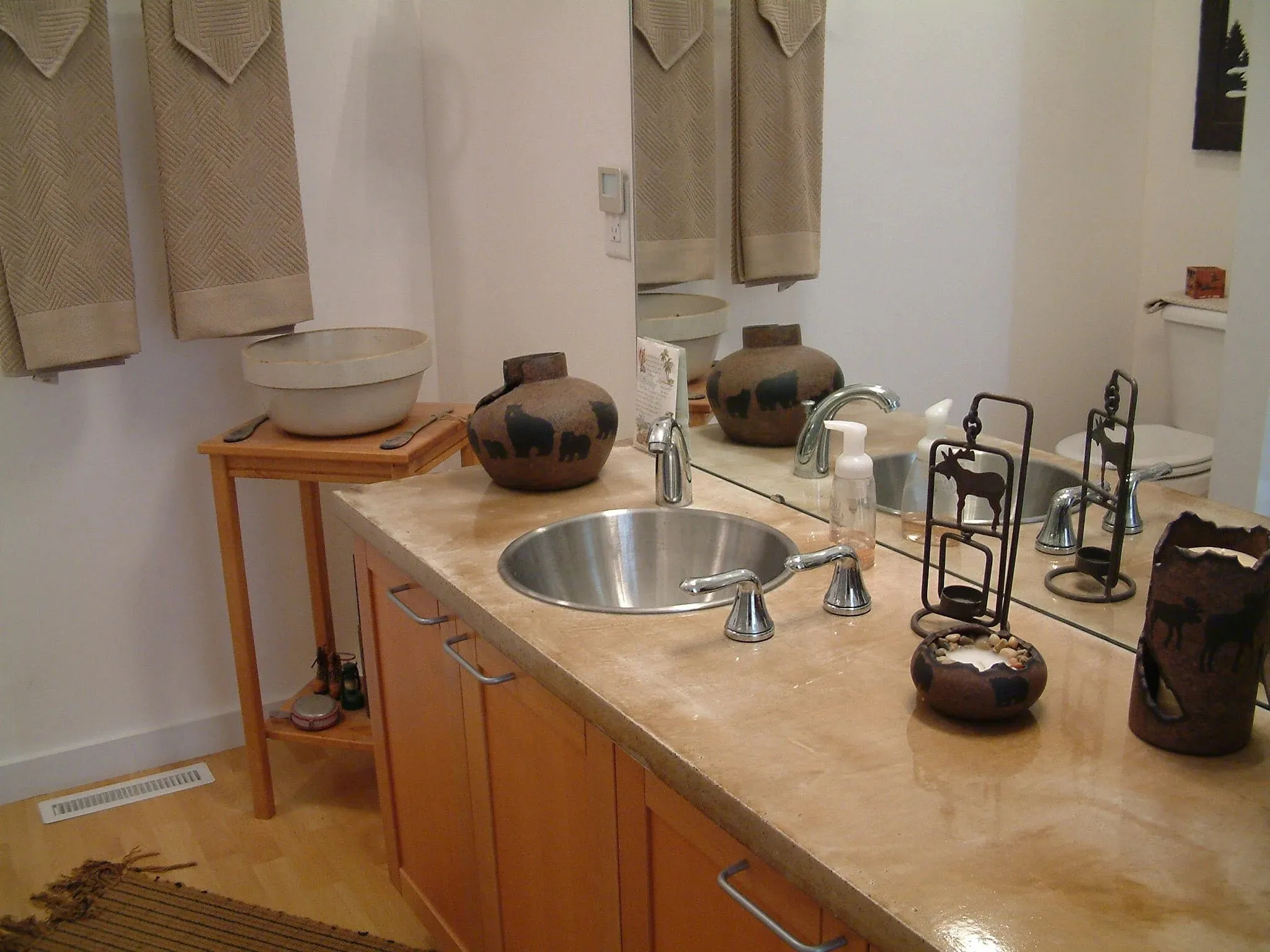Bath counter with round stainless sink and warm wood cabinetry