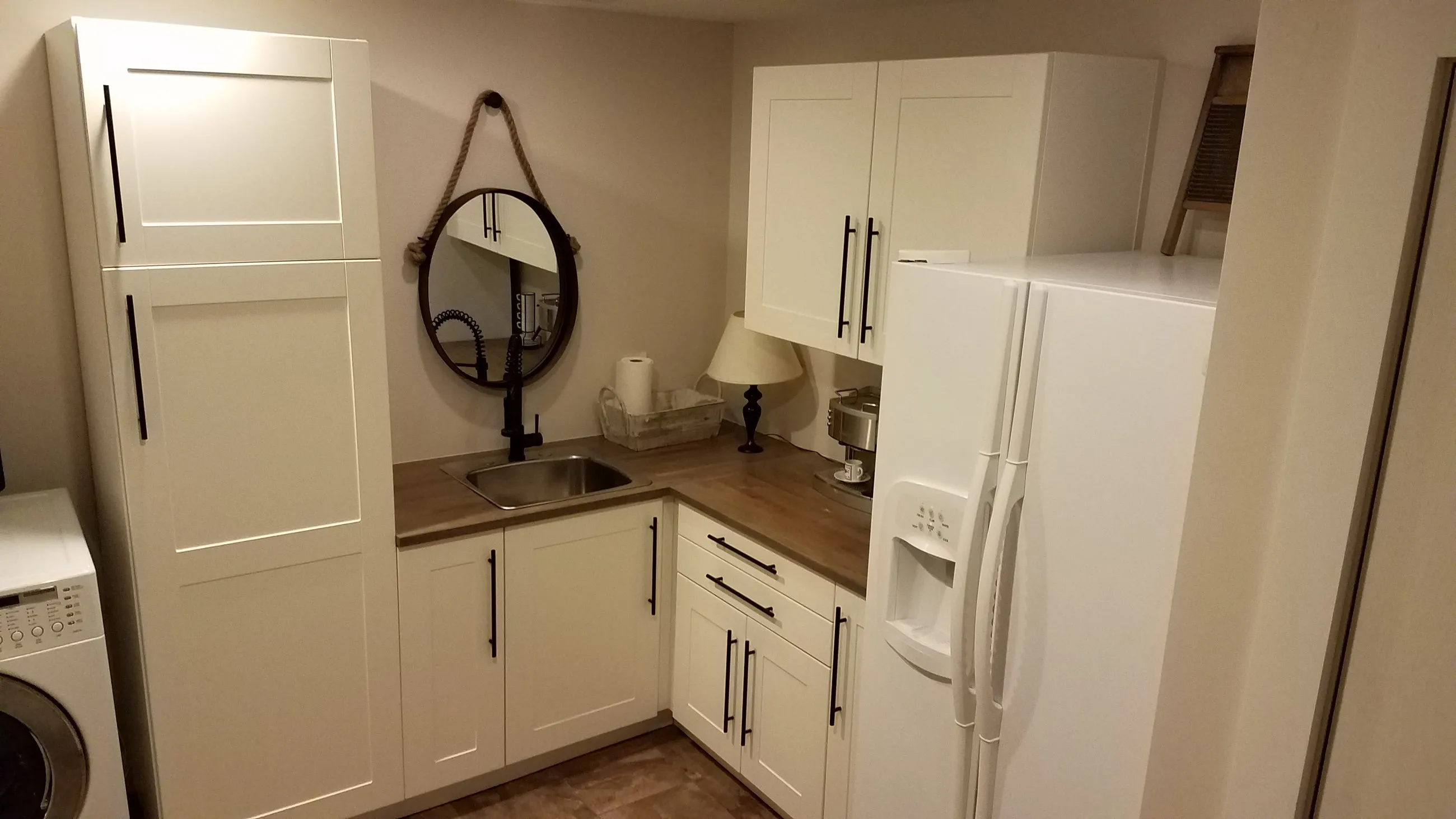 White shaker cabinetry and utility sink in a basement laundry room