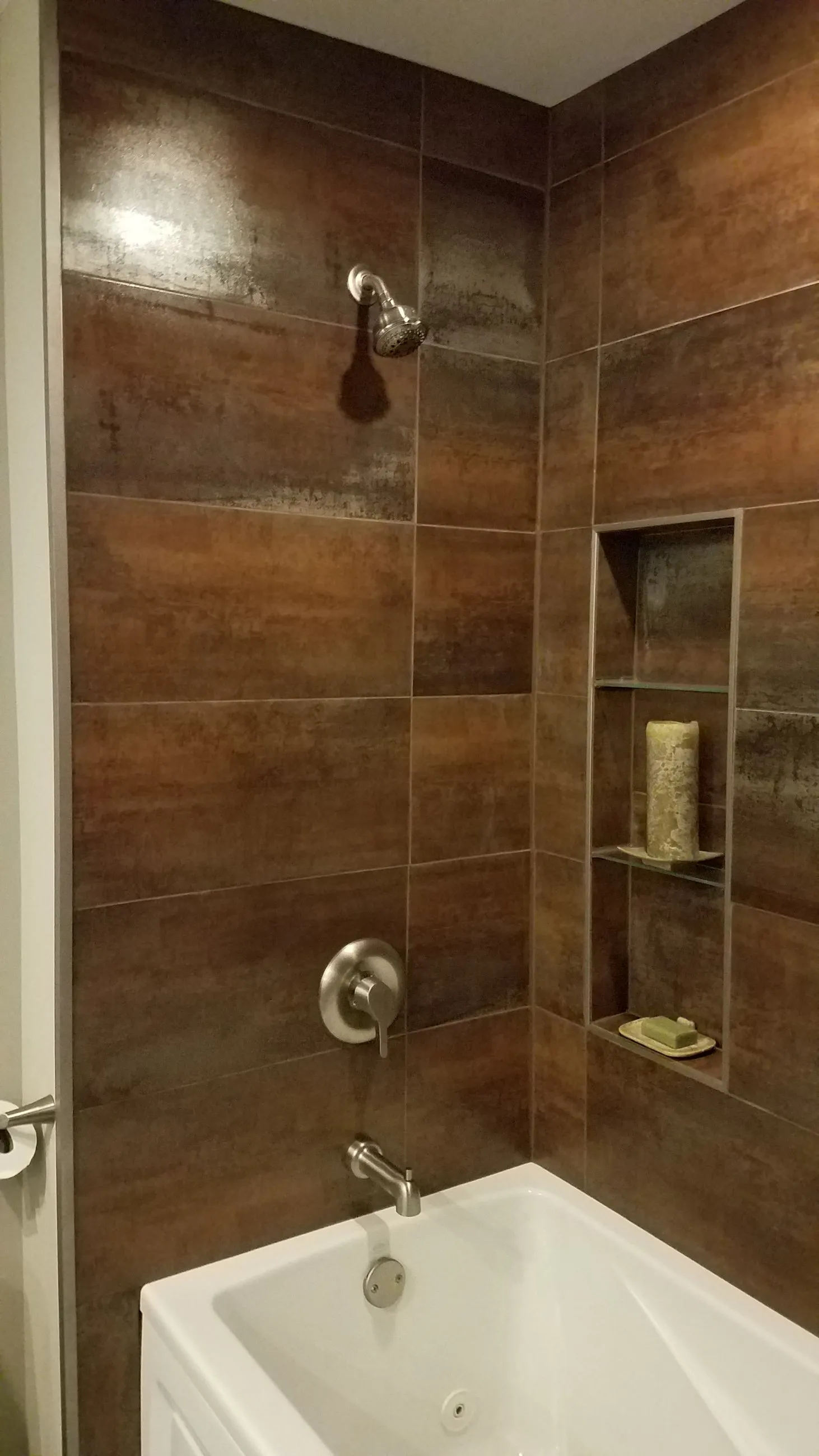 Rust-toned metallic tile tub surround with an inset shower niche