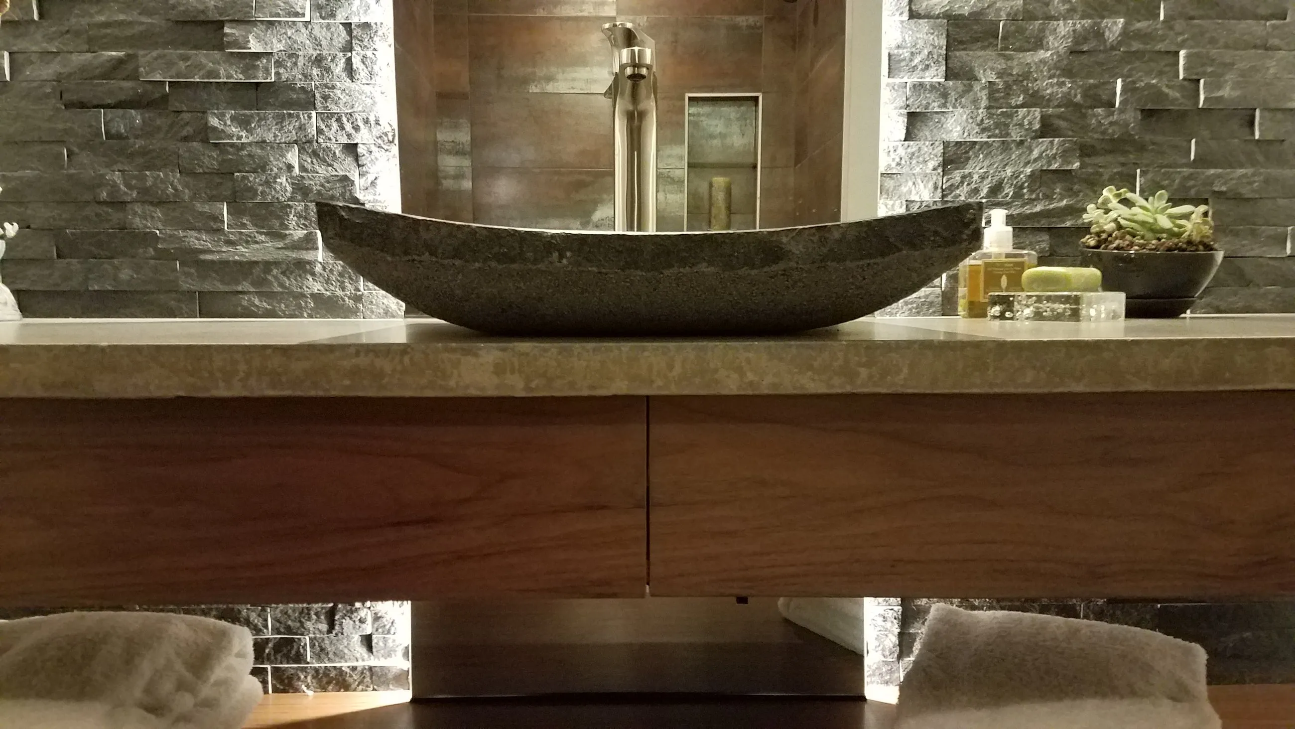 Carved stone vessel sink on a concrete-look floating counter