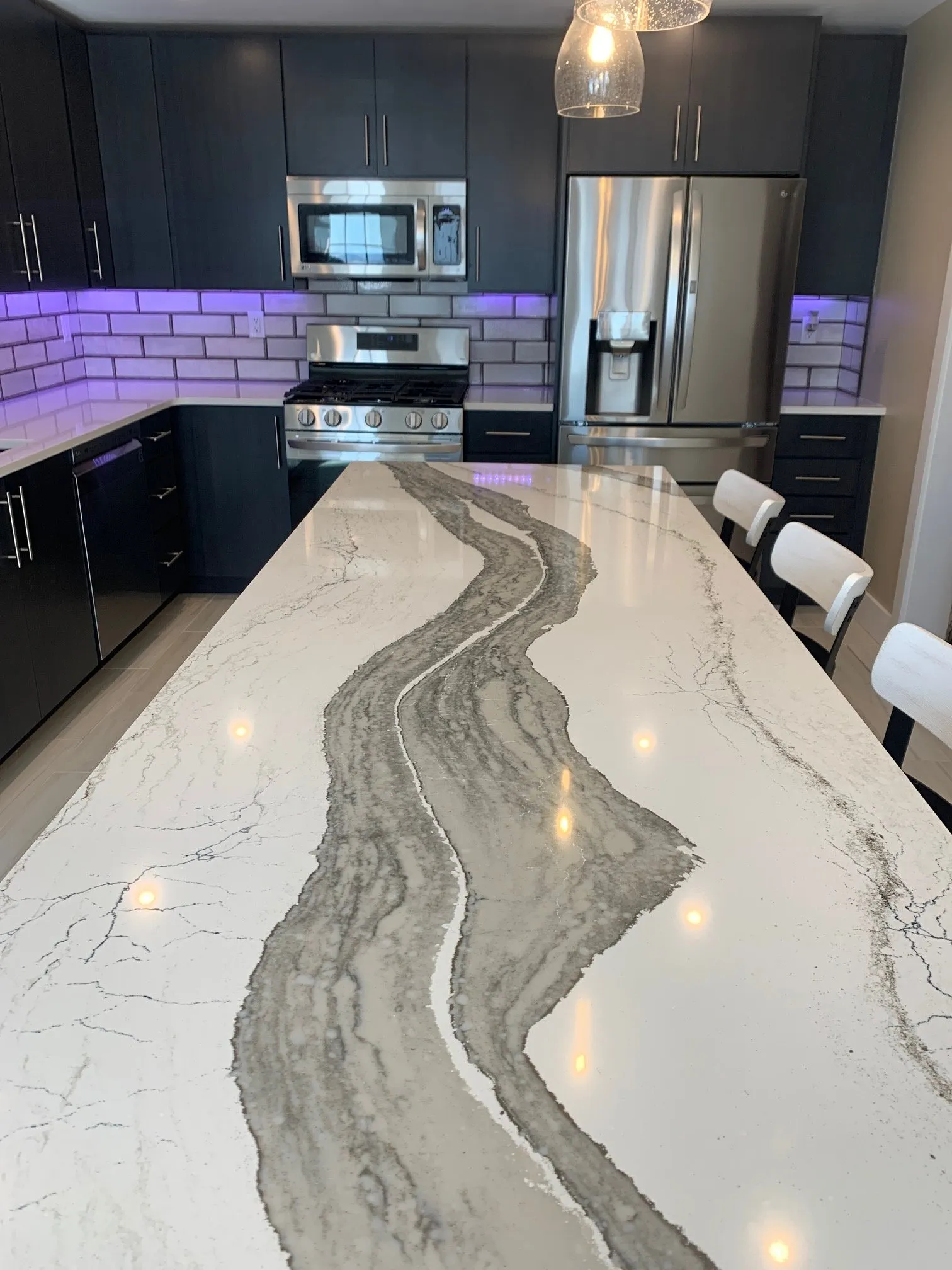 Veined quartz island top running the length of the kitchen