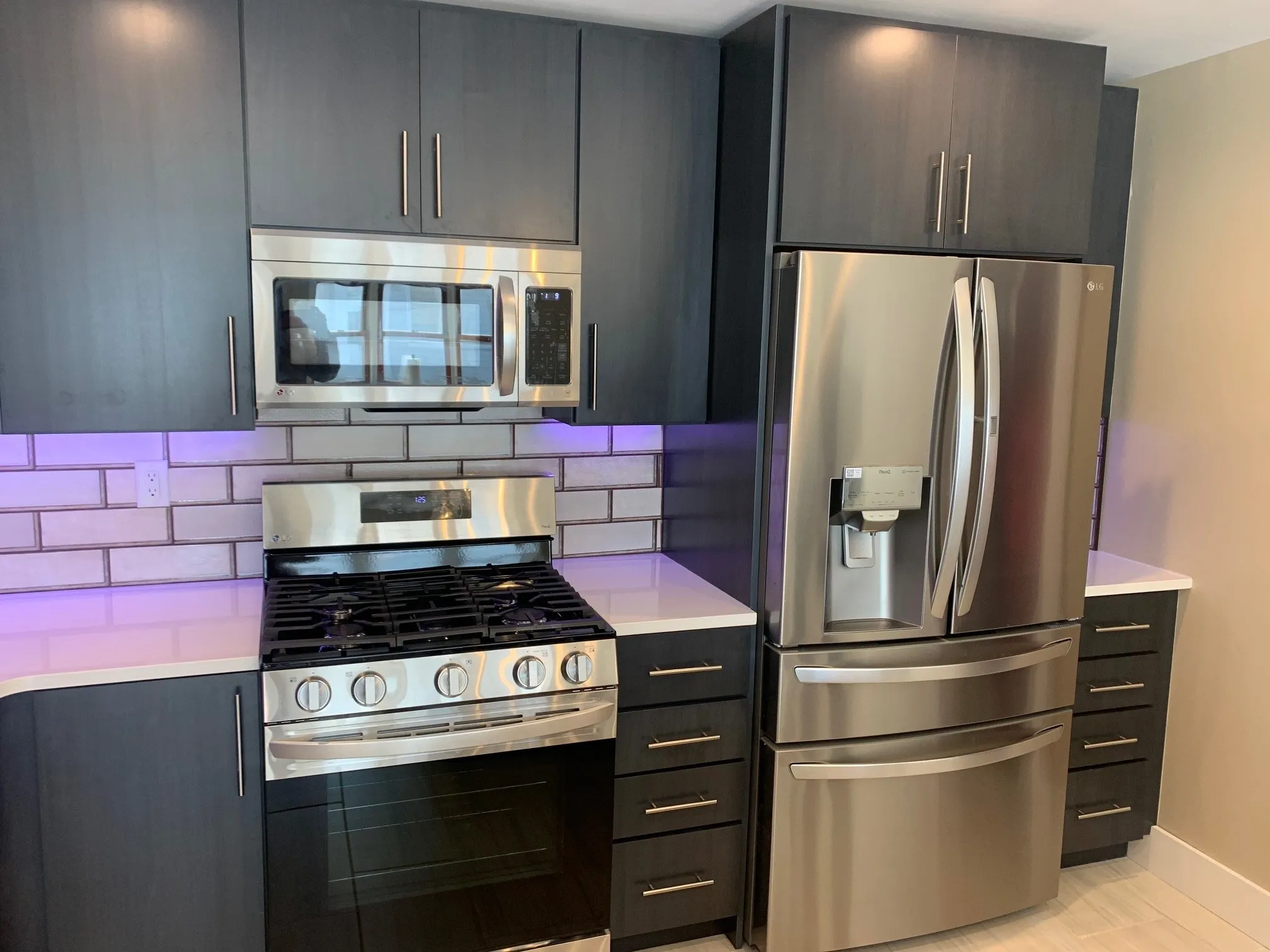 Stainless range and refrigerator set into dark blue cabinetry