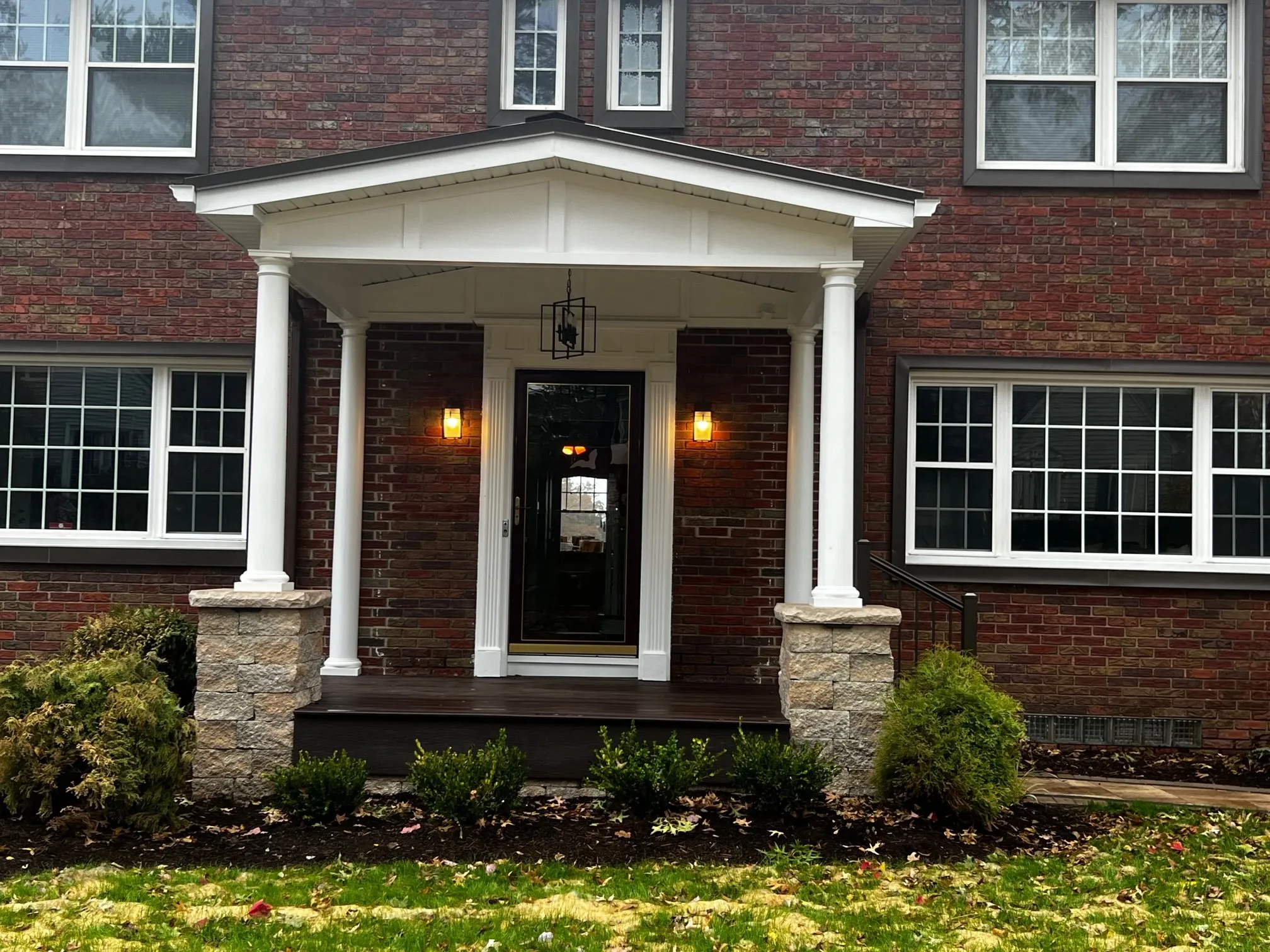 Porch roof on white columns and stone piers over the new deck