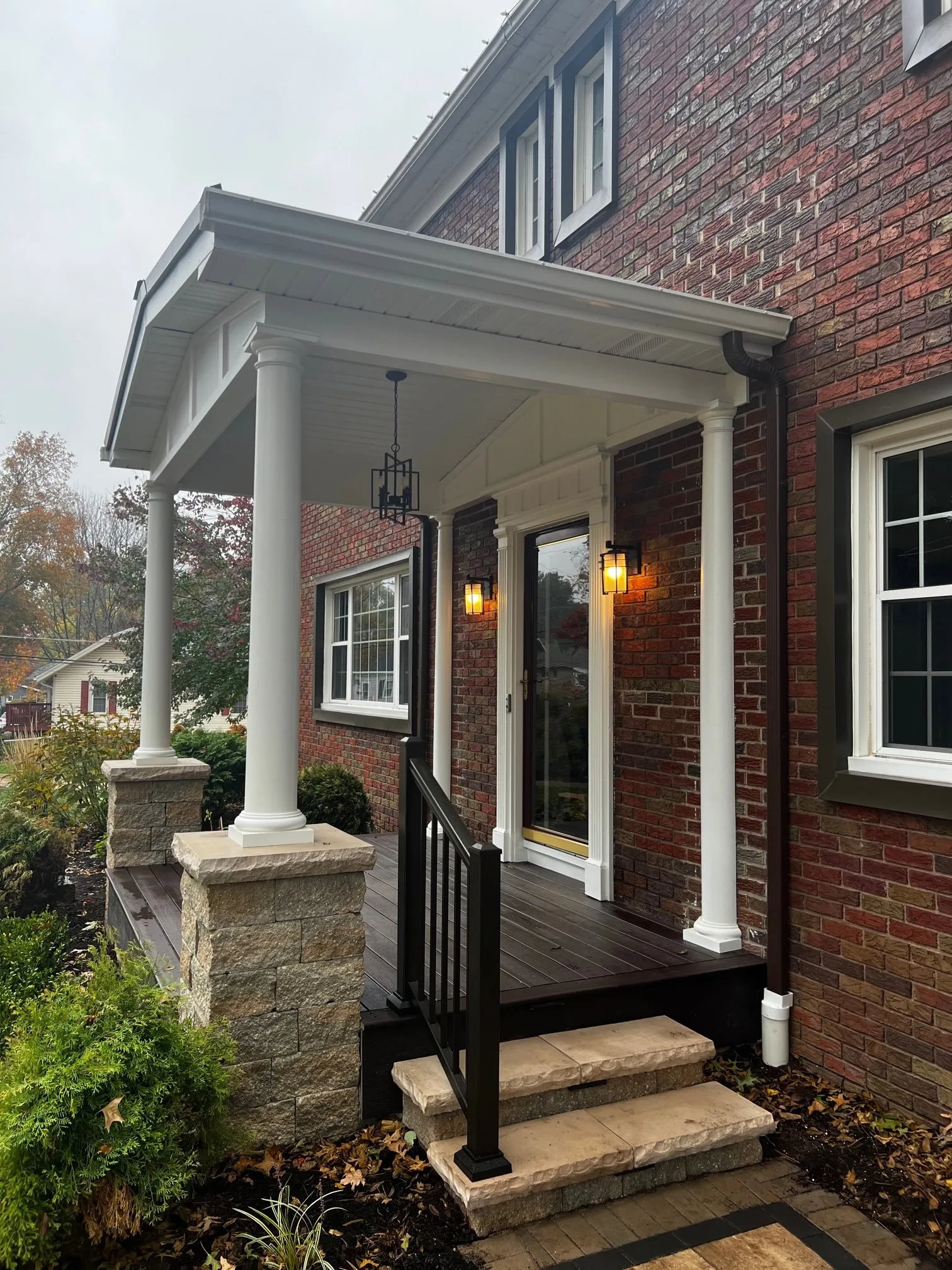 Front porch steps with black railing and stone pier