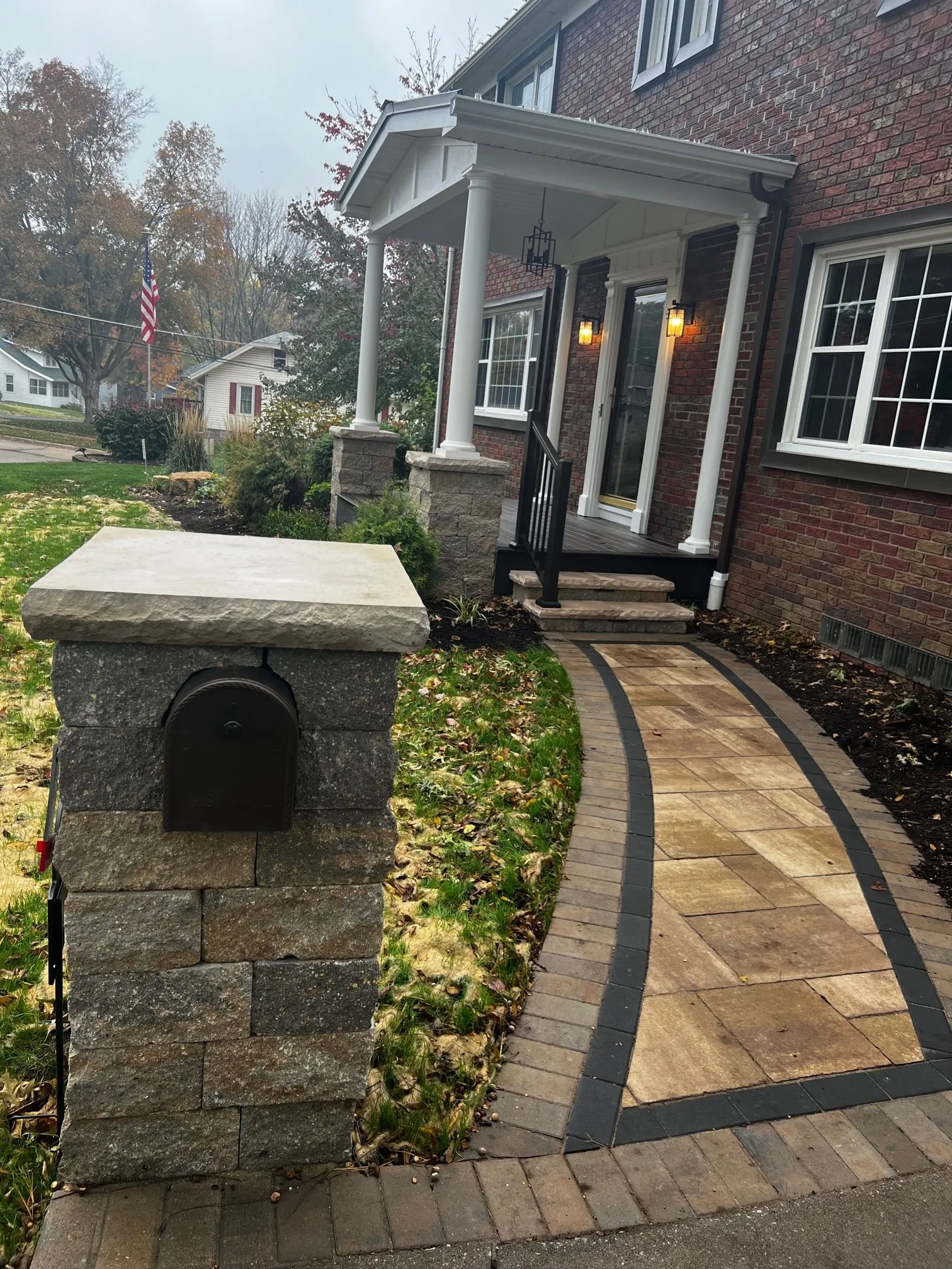 Stone mailbox pillar and paver walkway to the porch