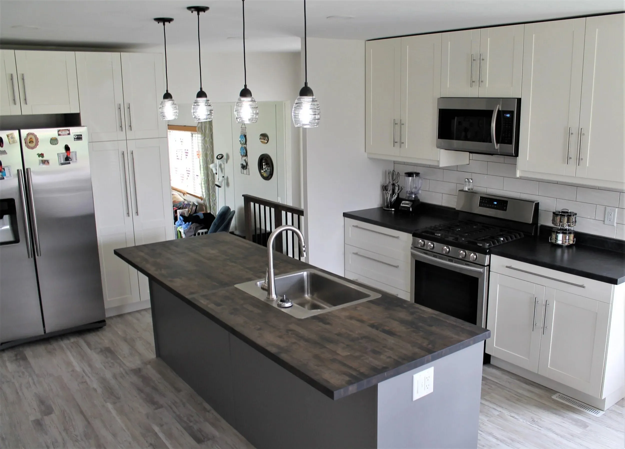 Remodeled kitchen with white cabinetry and a dark-topped island