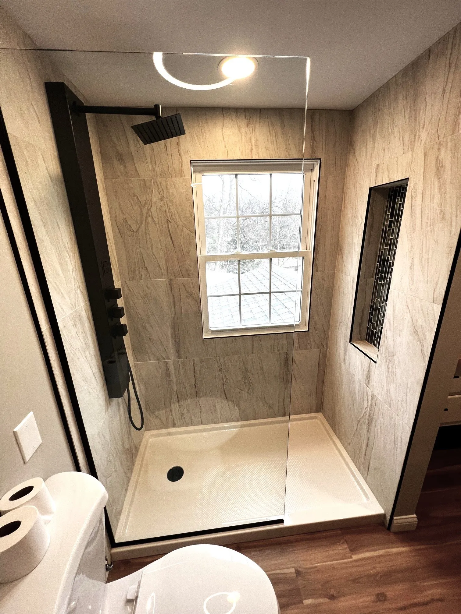 Walk-in shower with rain head, window, and inset niche