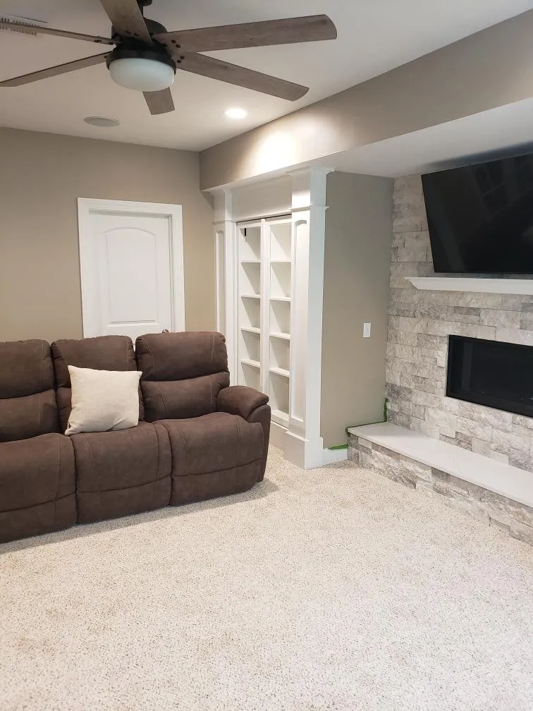 Sofa beside white built-in shelving and stone veneer