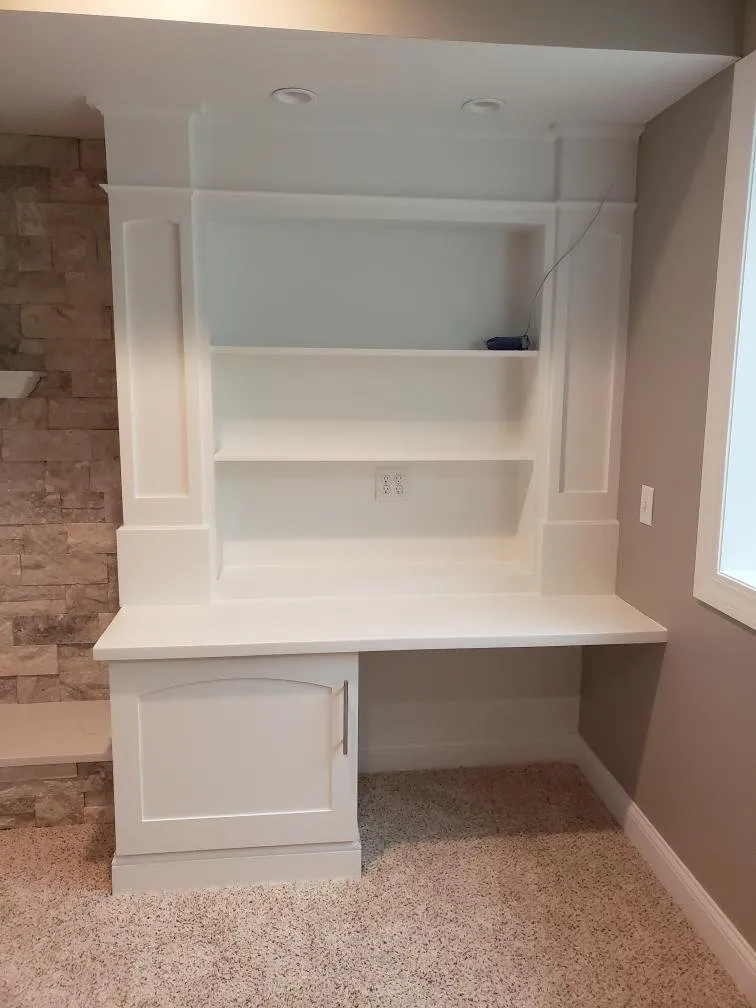 White built-in desk and shelving against stone veneer
