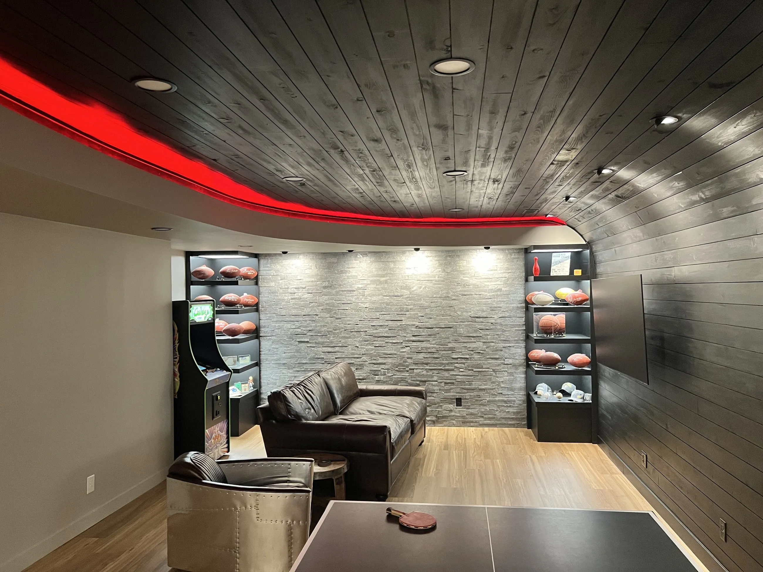 Dark plank ceiling, stacked stone wall, and lit display shelves