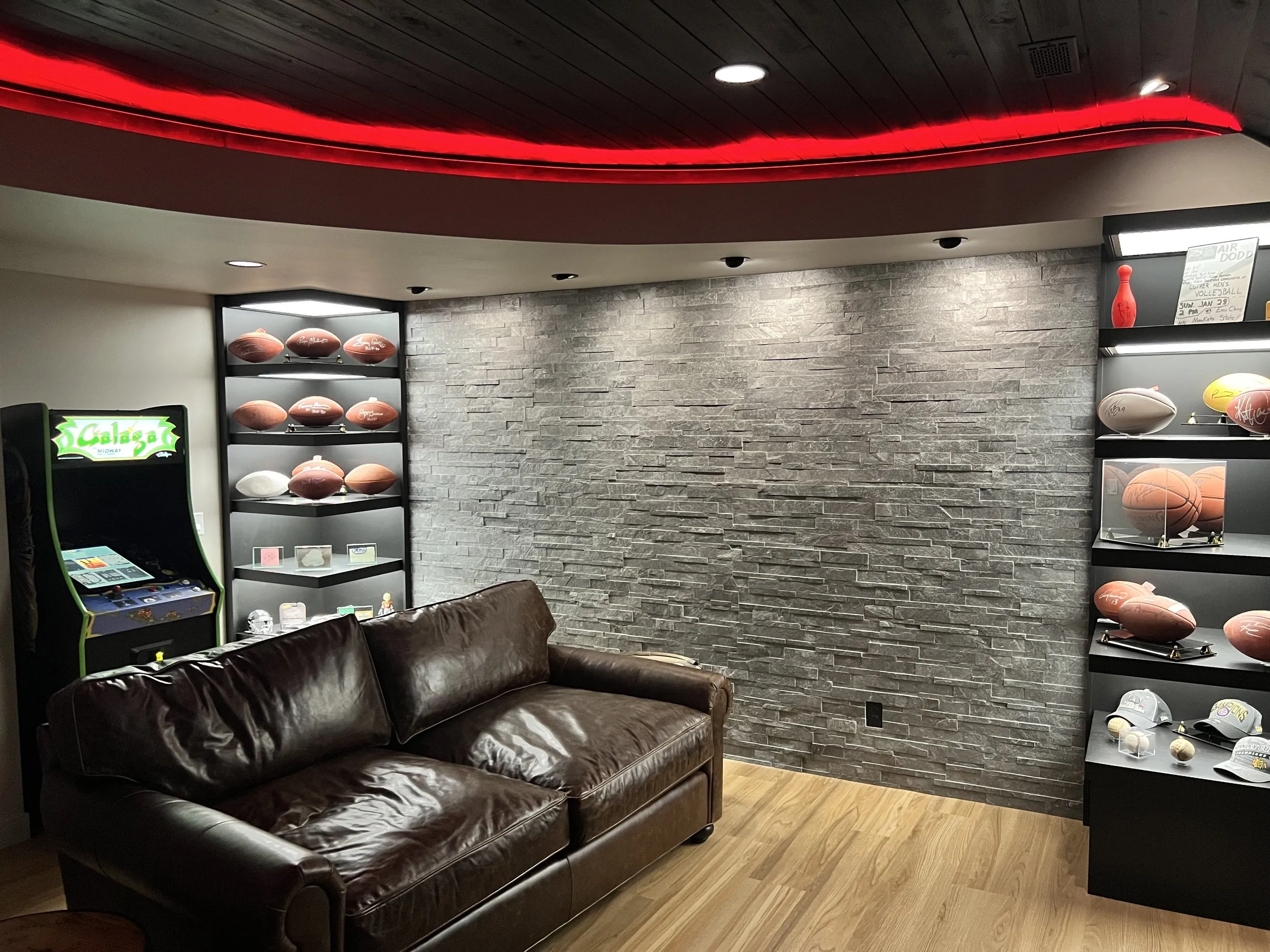 Football collection on lit shelves against stacked stone