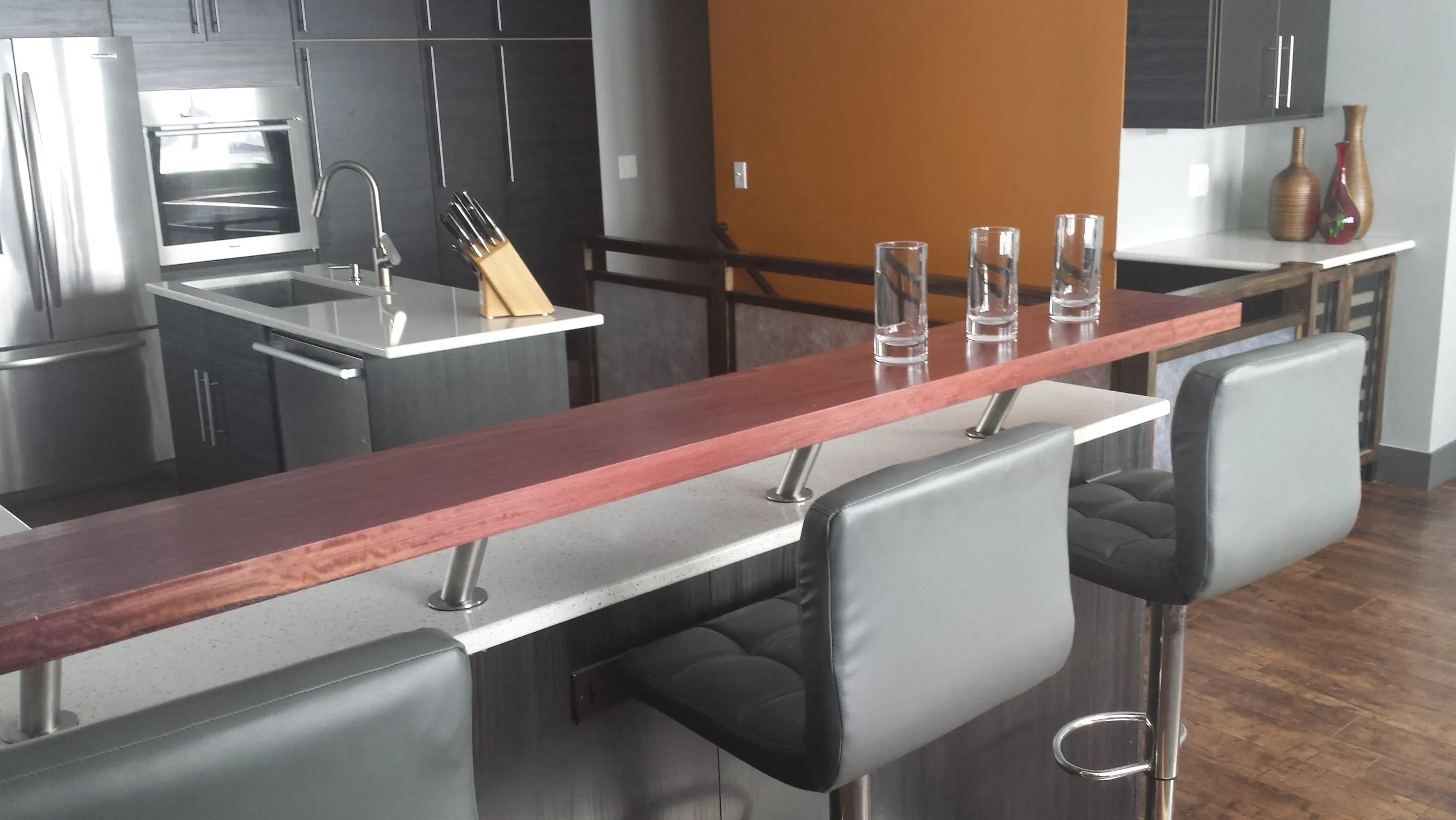 Raised wood bar rail running along the quartz island