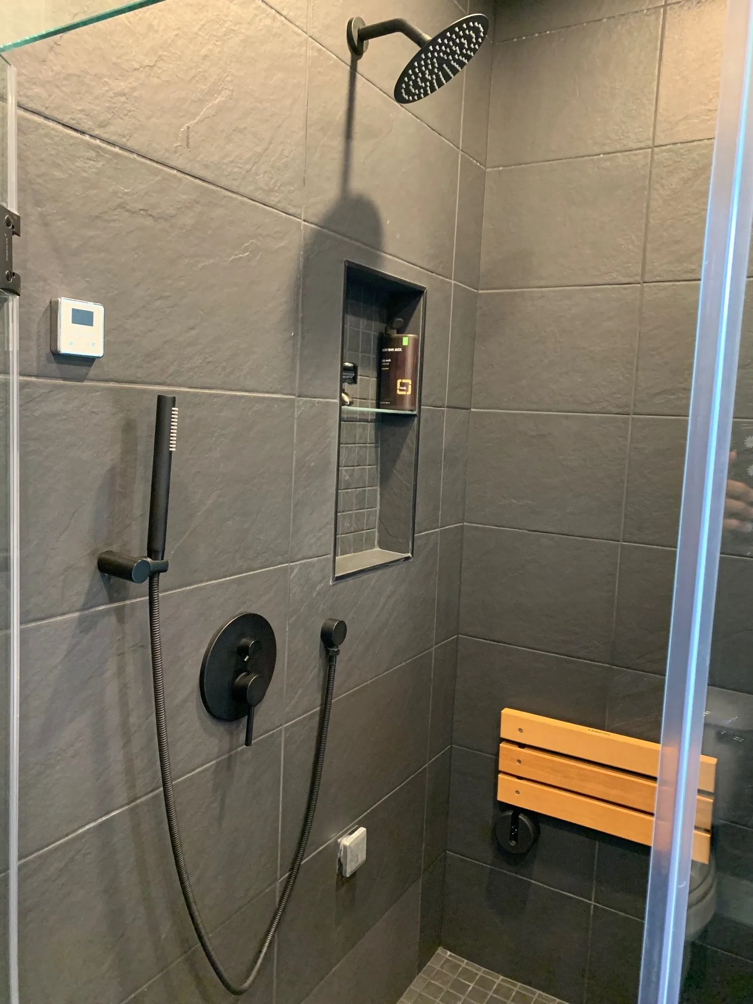 Grey tile steam shower with rain head and teak bench