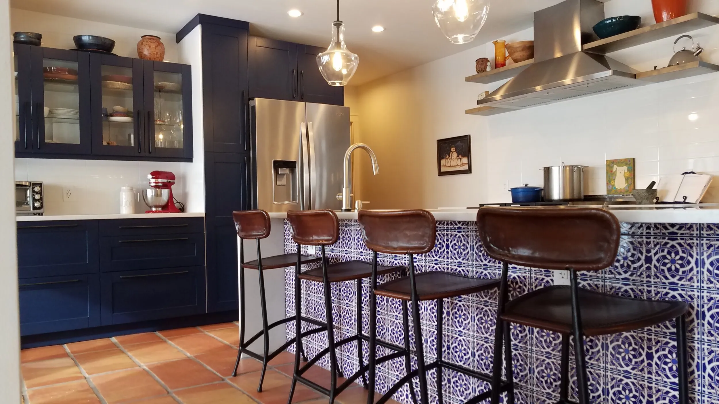 Leather stools at the island under glass pendants