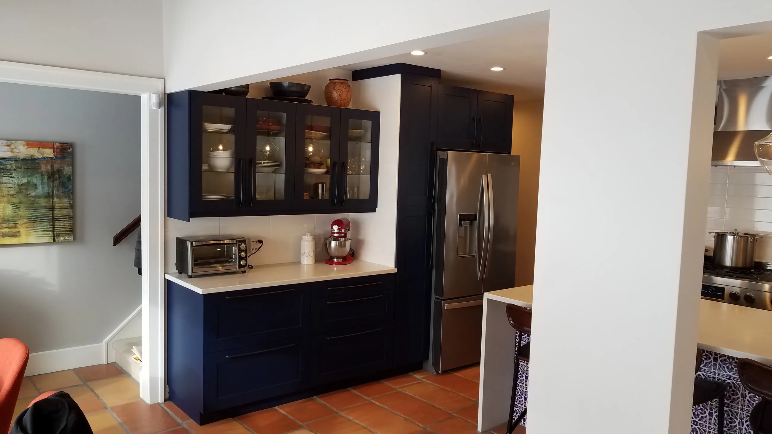 Navy cabinetry and white counters along the refrigerator wall