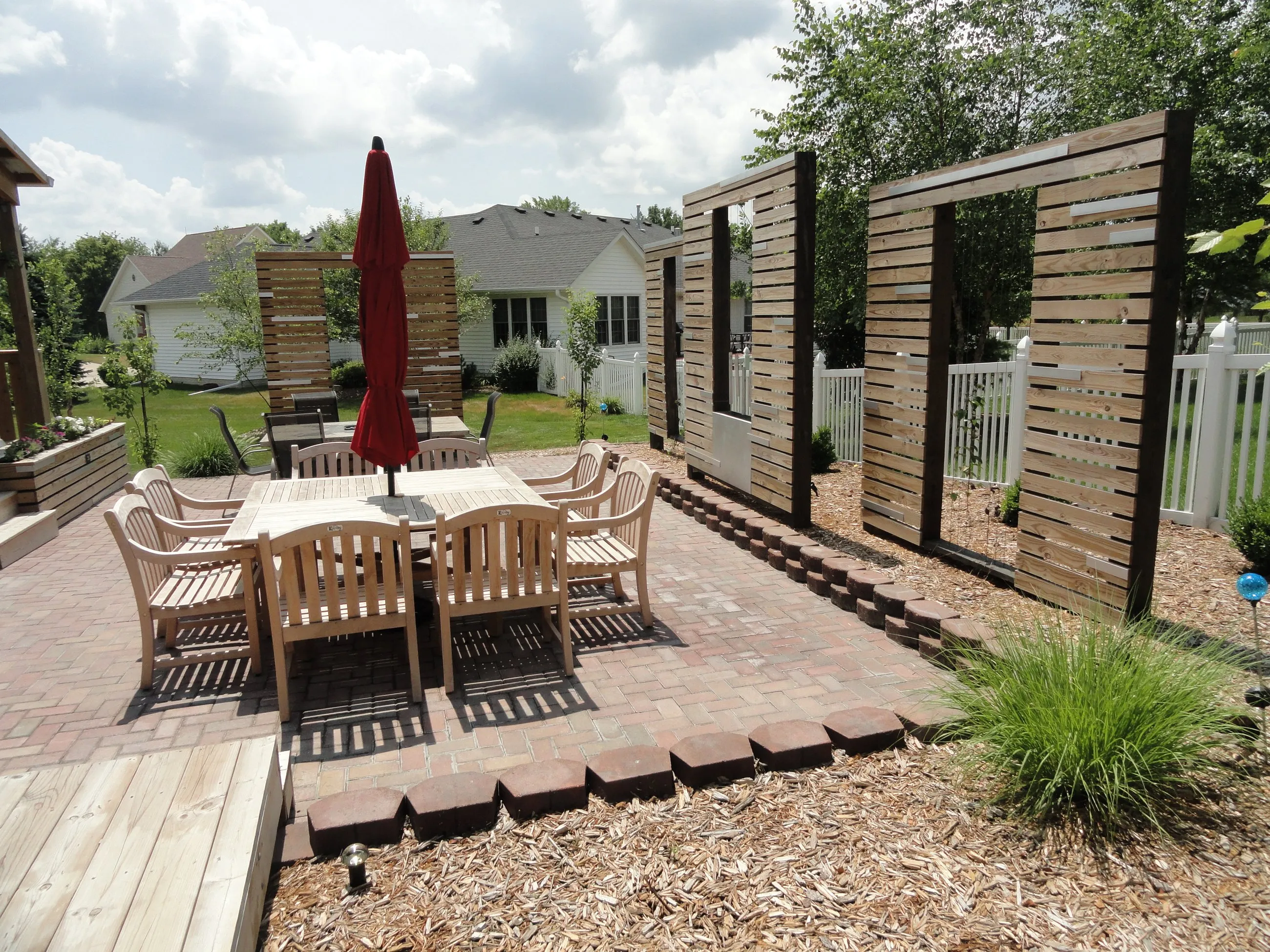 Cedar slat privacy screens with stainless panels around an outdoor dining terrace