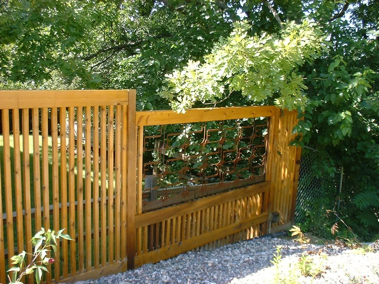 Vertical cedar slat fence with an inset upcycled metal panel