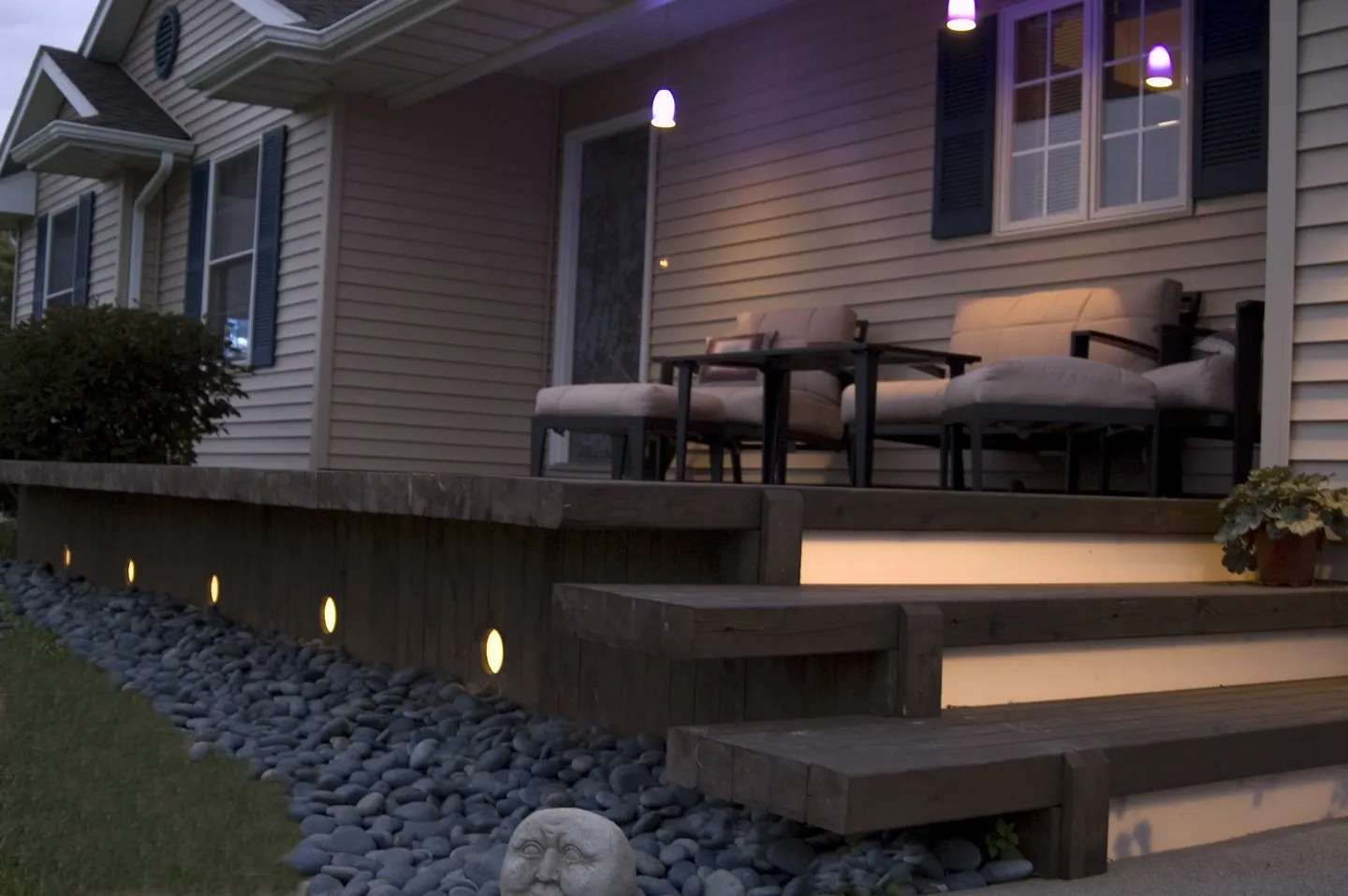 Lighted deck steps over a river rock bed