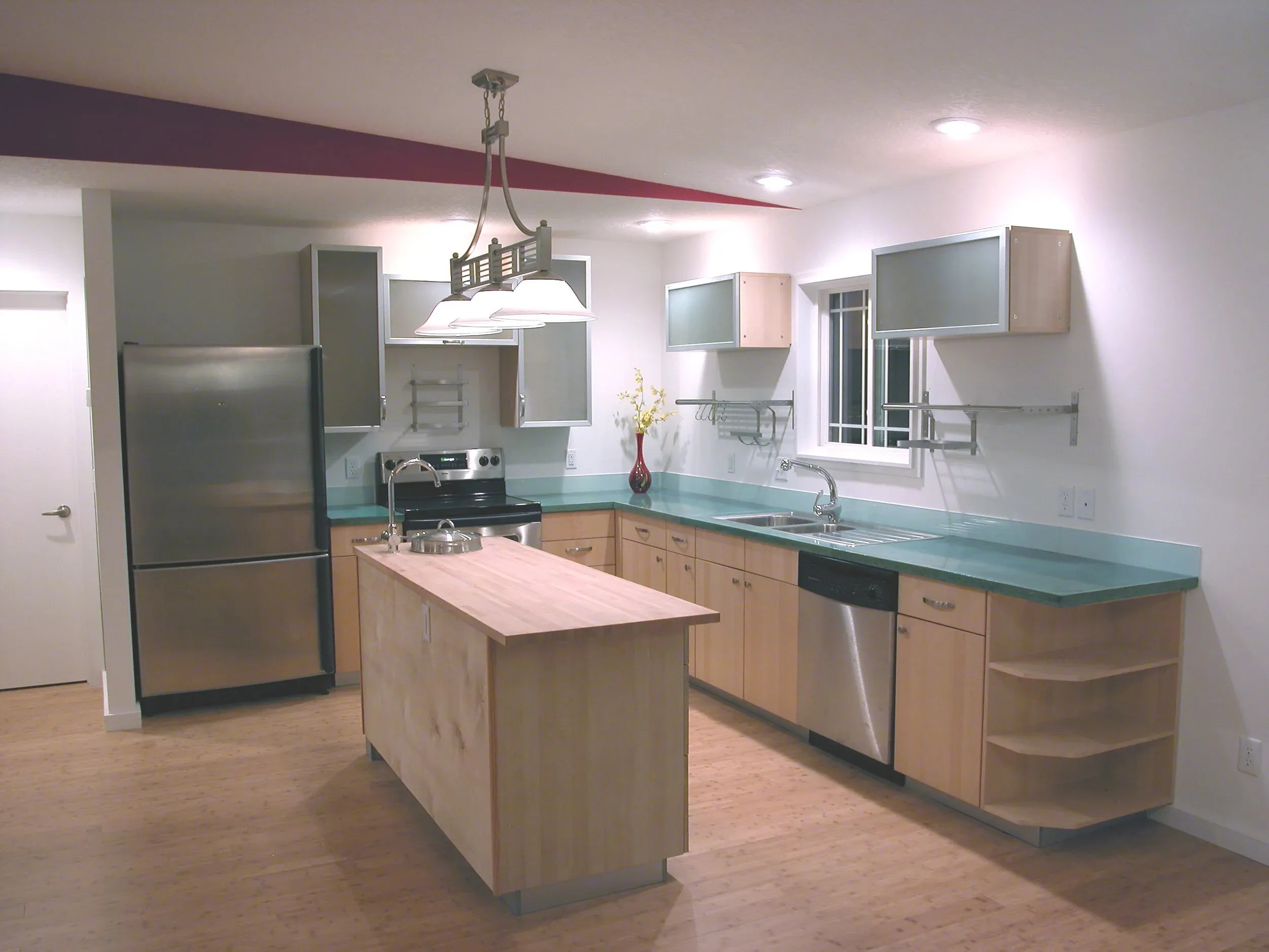 Kitchen with teal counters, light cabinetry, and curved island