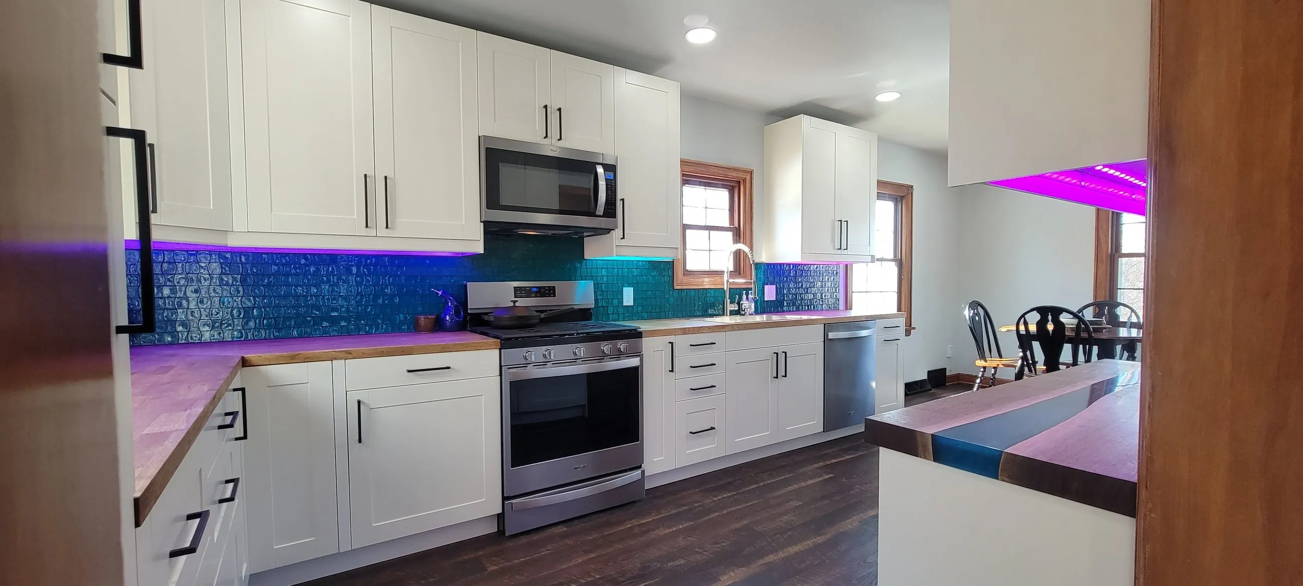 White cabinetry and resin river counter along the range wall