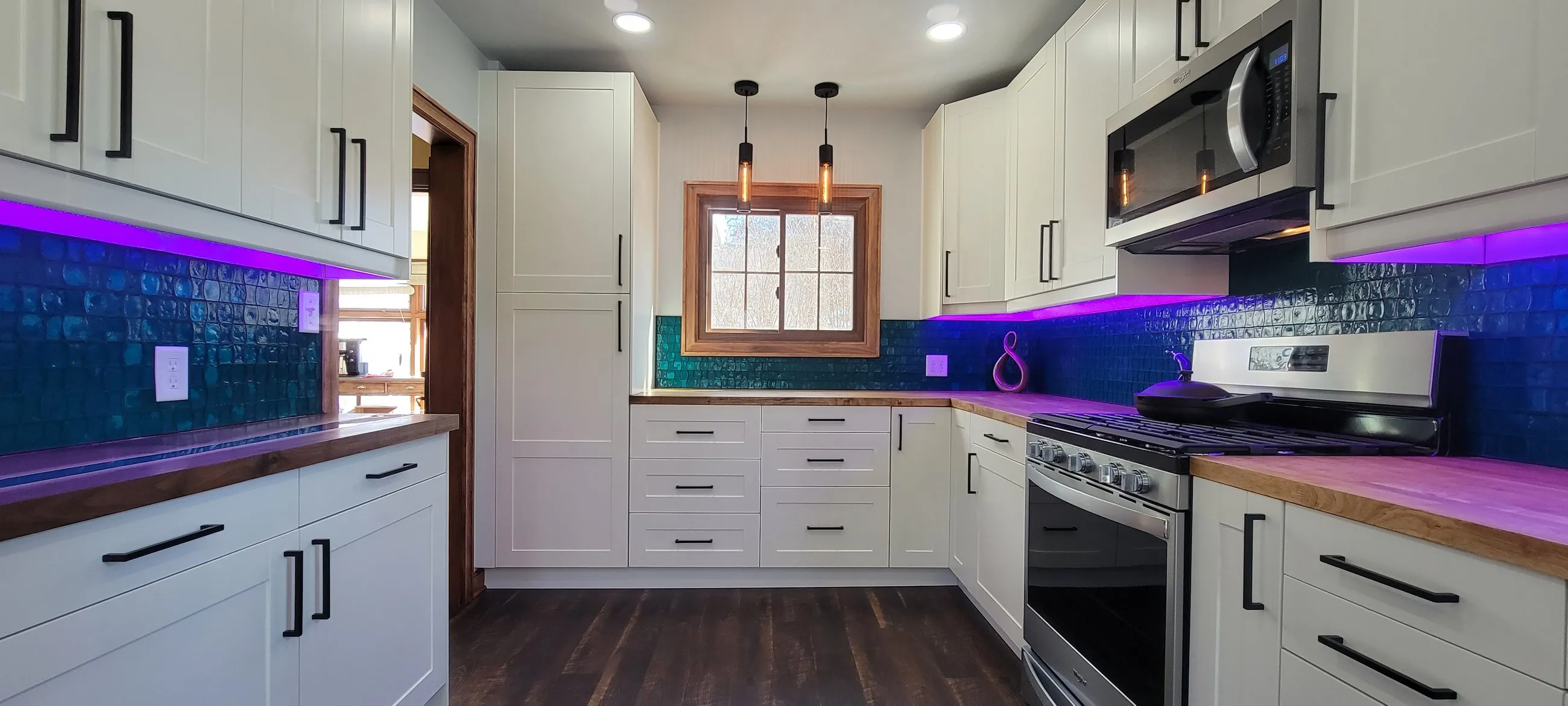 Window wall with blue tile and white cabinets