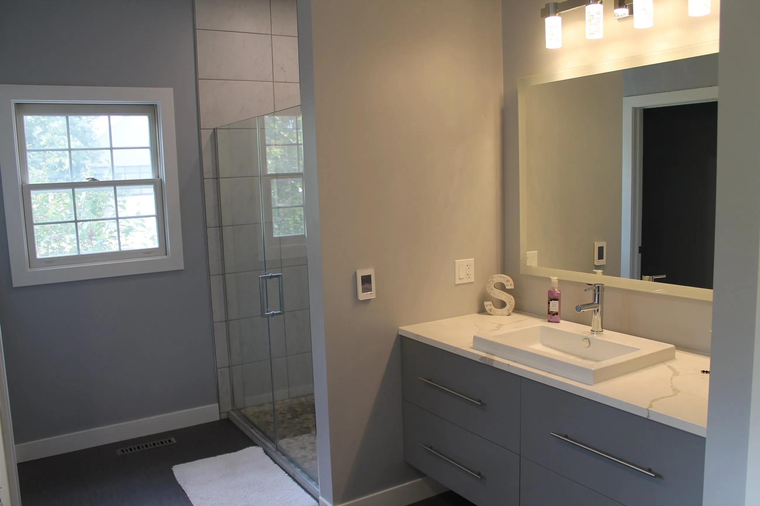 Walk-in glass shower beside the grey vanity