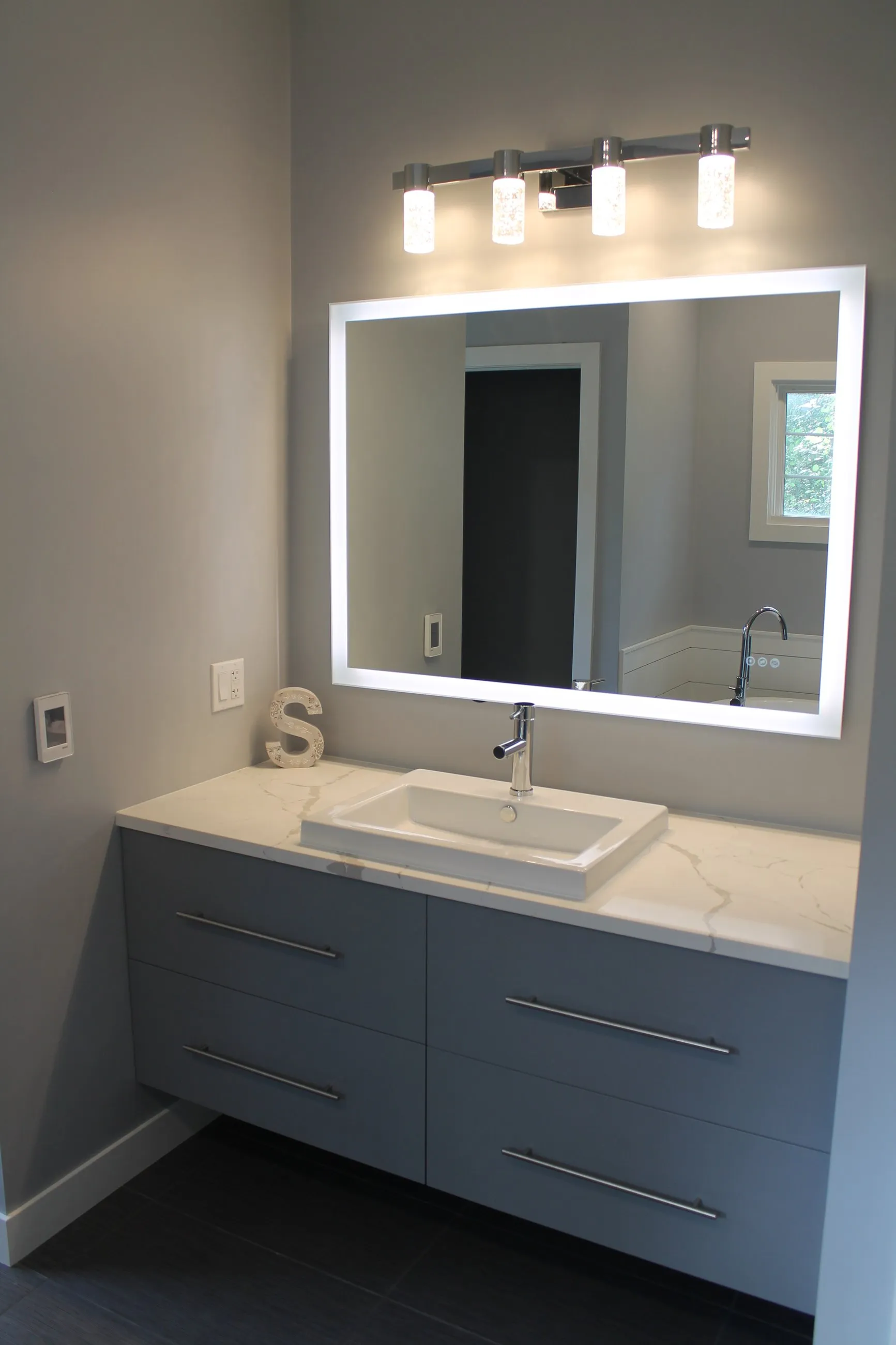 Lighted mirror over the grey floating vanity