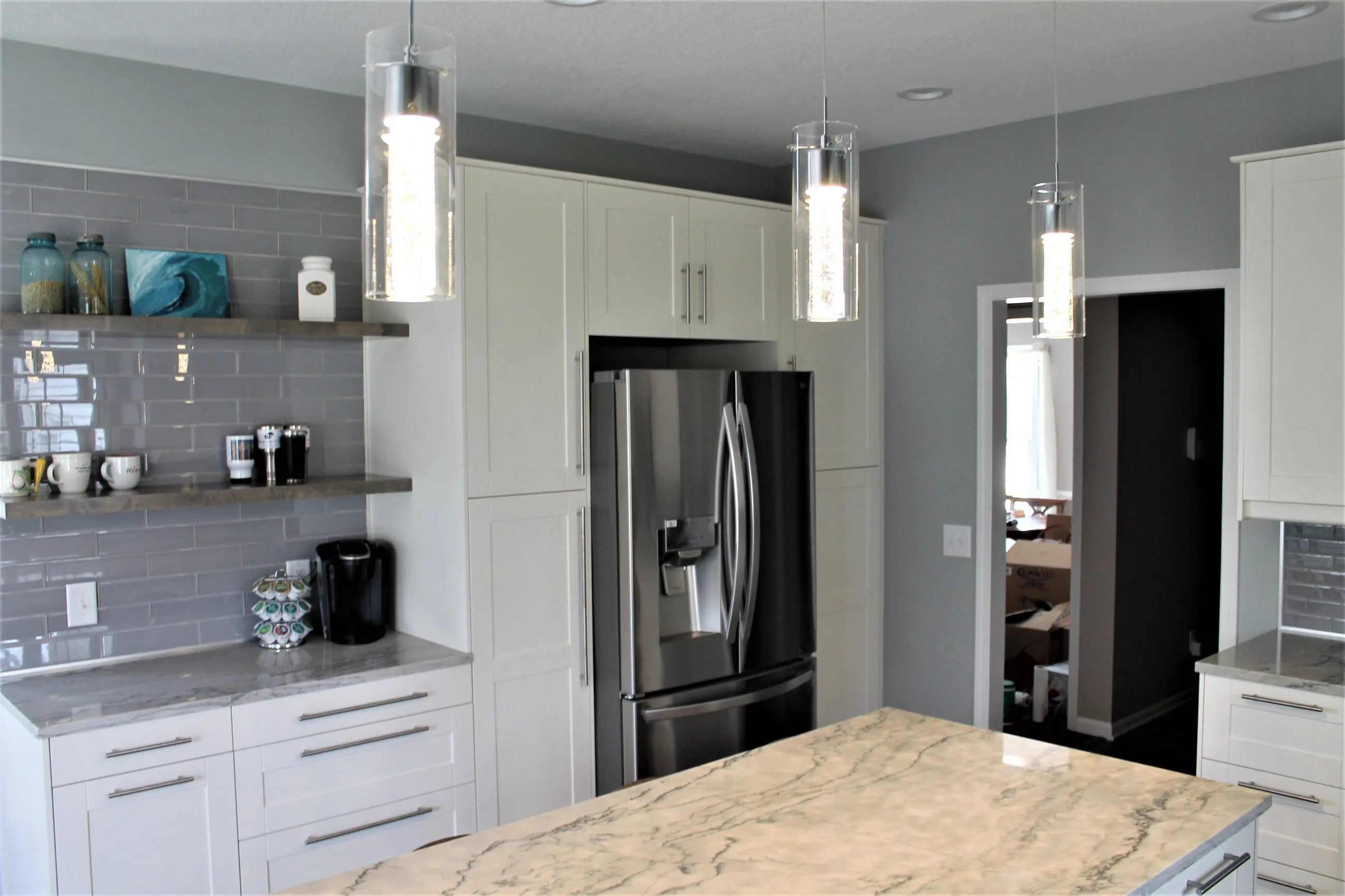 Stainless refrigerator flanked by white pantry cabinets