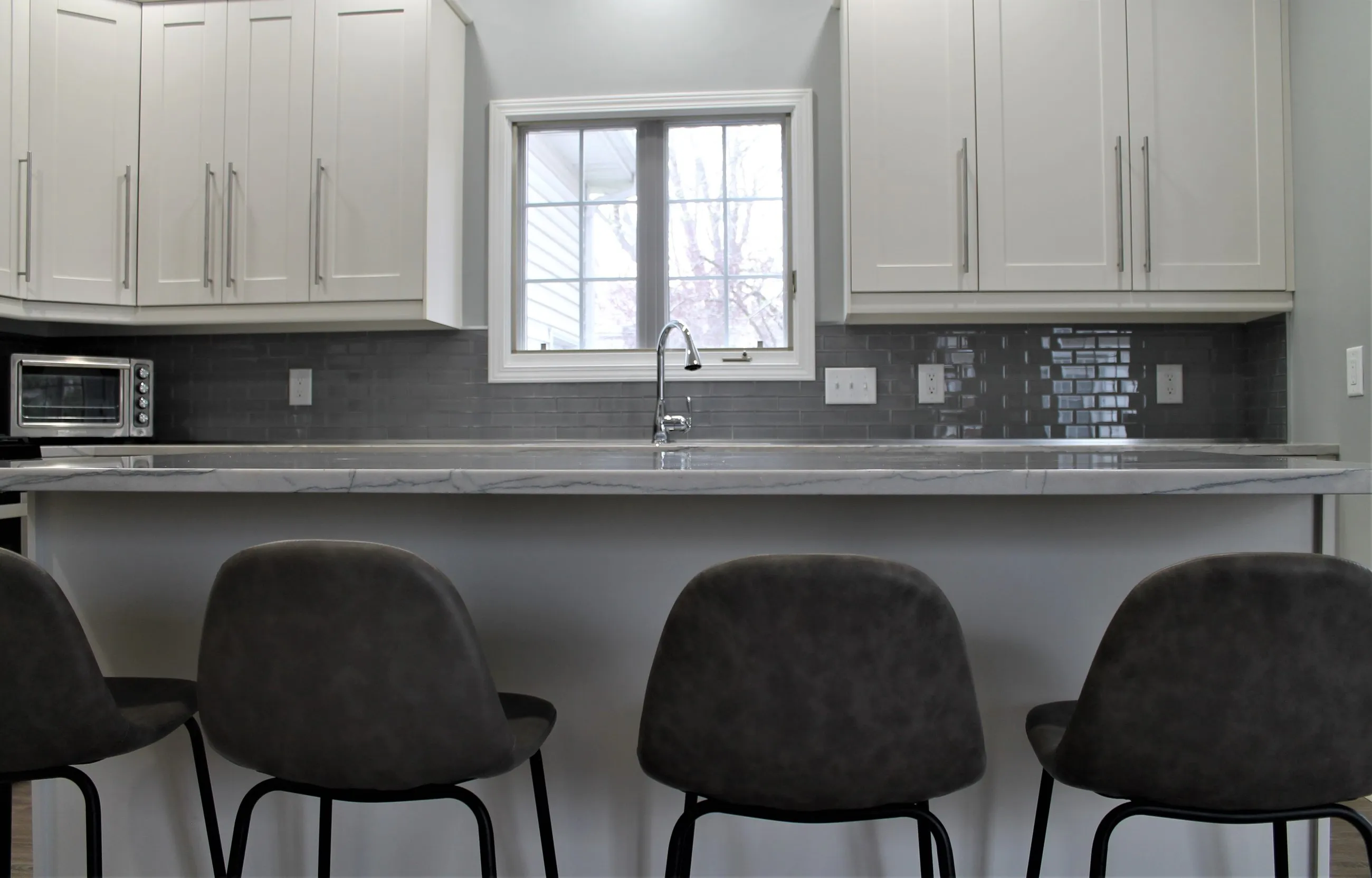 Breakfast bar seating at the grey subway tile wall