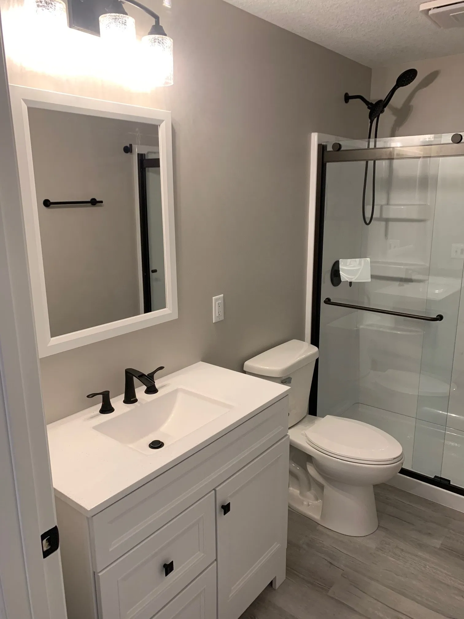 Basement bath with white vanity and glass shower
