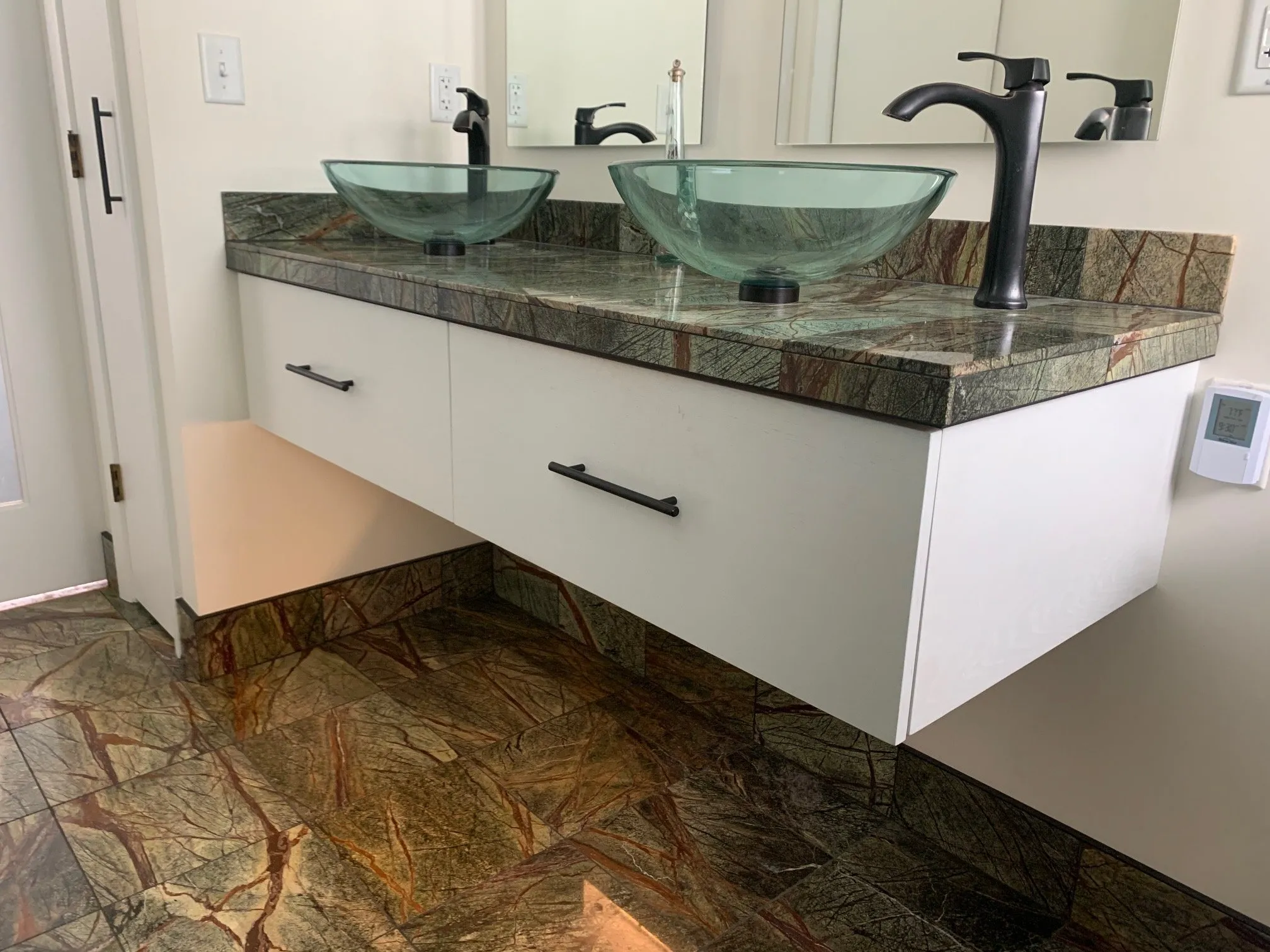 Double glass vessel sinks over white drawers and marble floor