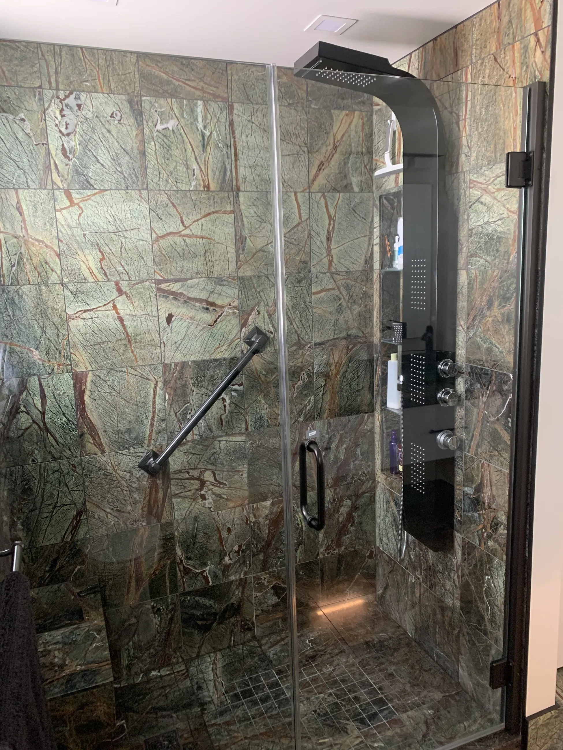 Walk-in shower tiled floor to ceiling in rainforest marble