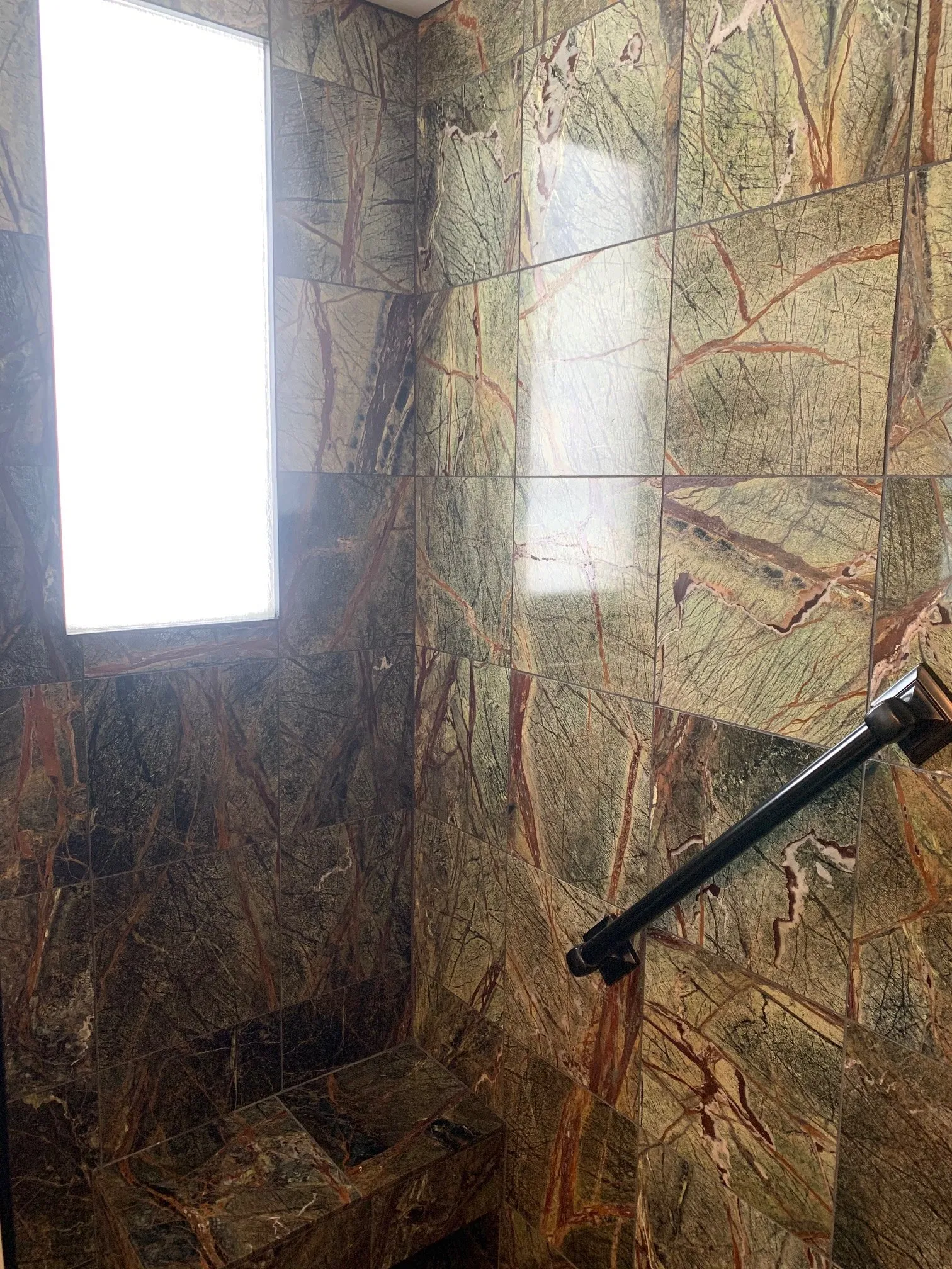 Rainforest marble shower walls with black fixtures